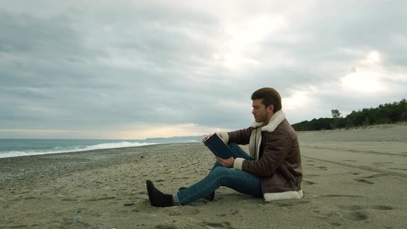 Young boy reads a book by the sea