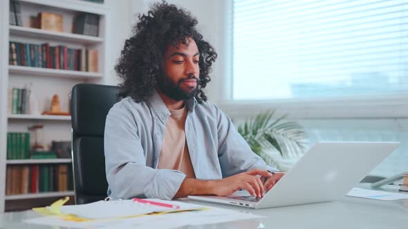 Young Arabian Man with Smile Starts Typing on Laptop Keyboard and Making Notes