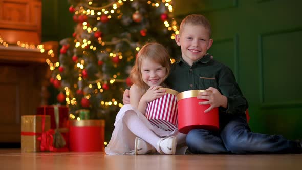 children with gifts in her hands sits in a cozy room