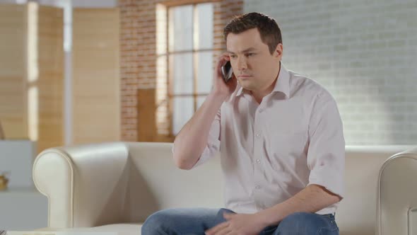 Young Man Discussing Business Problems in Phone Call at Home