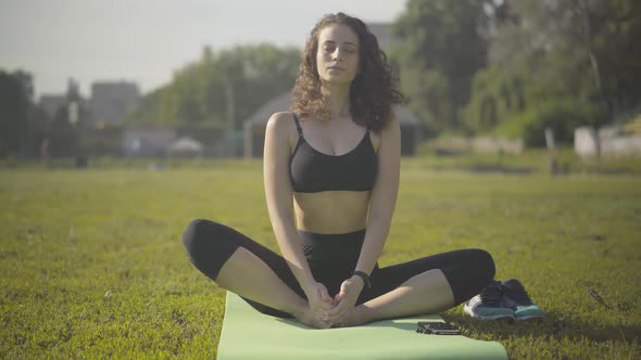 Portrait of Beautiful Caucasian Female Yogi Sitting on Exercise Mat in Lotus Position. Beautiful