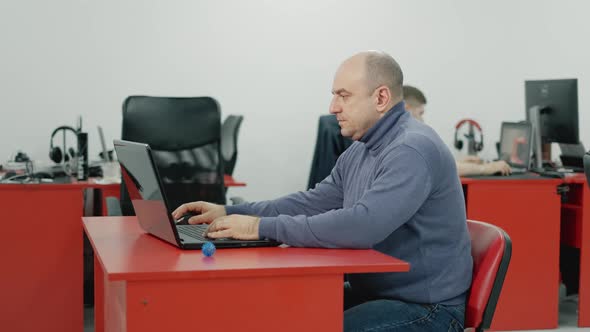 Mature 40s Man Works at the Computer and Kneads Tired Hands in the Office