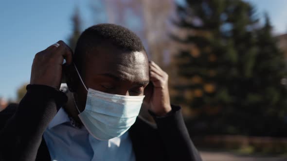 Portrait of African American Business Man in Mask, Smartphone in Hands. City Walk Down the Street