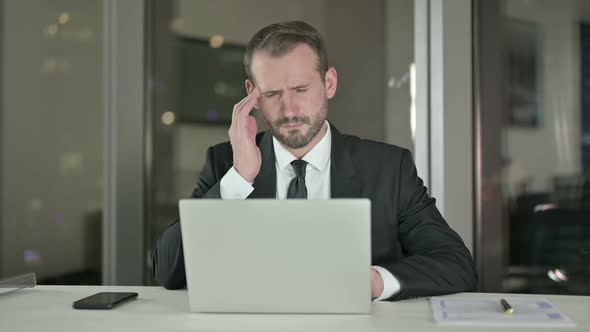 Stressed Businessman Having Headache in Office at Night