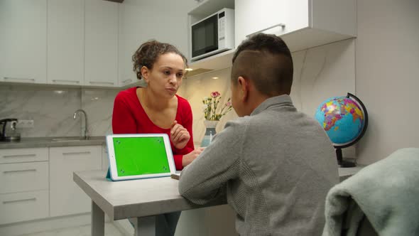 Woman Helping Son Studying with Elearning Platform Indoors