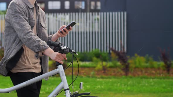 Young Man with Bicycle and Smartphone in City
