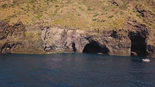 Aerial View on White Boat Anchored Near Cave of Lipari Island in Mediterranean Sea. Some People on