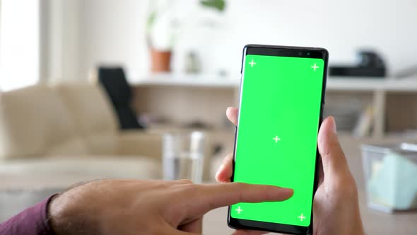 Close Up of Man Using a Modern Smartphone with Green Screen Chroma Mock Up on It