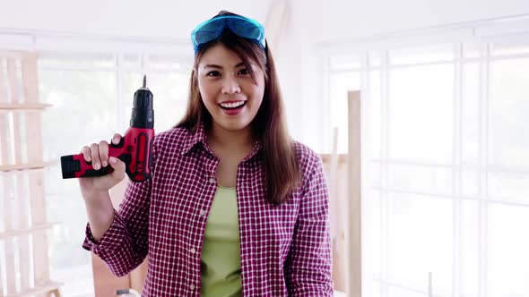 Portrait of young woman holding screwdriver in her carpentry workshop