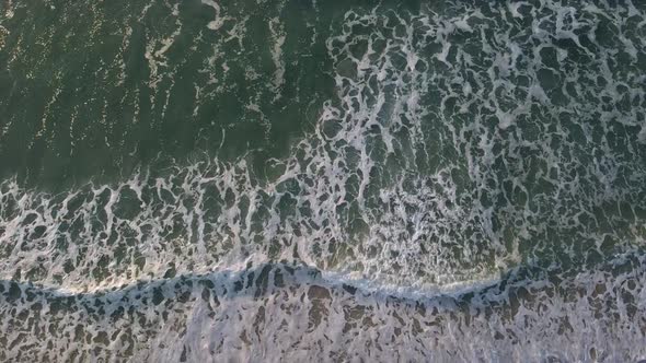 Waves breaking cleanly towards the beach at a surf spot. White horses visible behind the wave with a