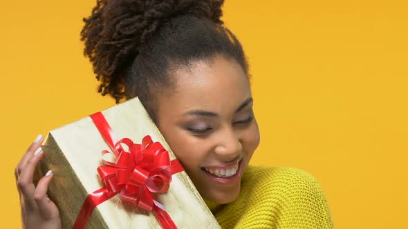 Smiling African Female Holding Present Box With Red Ribbon on Bright Background