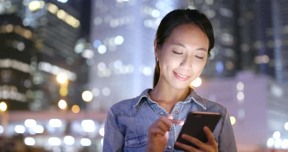 Woman use of mobile phone in Hong Kong city at night 