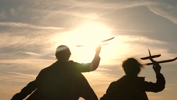 Two Girls Play with a Toy Plane at Sunset. Dreams of Flying. Happy Childhood Concept