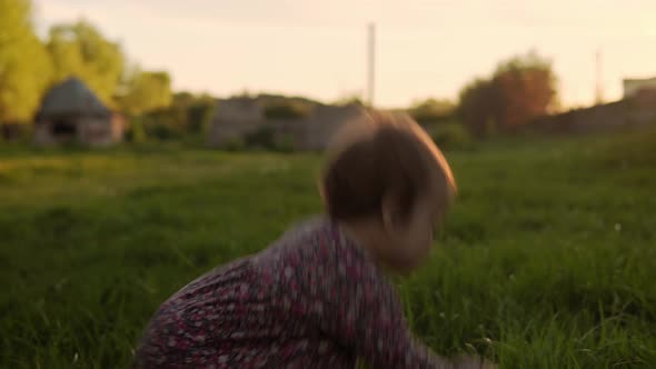 Authentic Cute Little Infant Baby Girl in Dress Walking in Park on Tall Grass at Spring Sunset