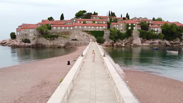 Aerial View of Beautiful Girl Going Along the Bridge to the Settled Island