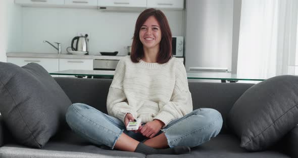 Excited Young Gamer Brunette Girl Sitting on a Couch Playing and Winning in Video Games on Sofa