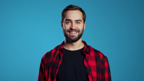 Handsome European Man with Trendy Beard in Red Plaid Shirt on Blue Studio