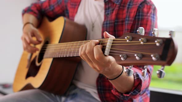 Young Man Playing Guitar Sitting on Windowsill