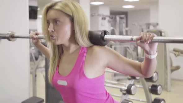 Camera Follows Movement of Concentrated Confident Woman Squatting with Weights on Shoulders