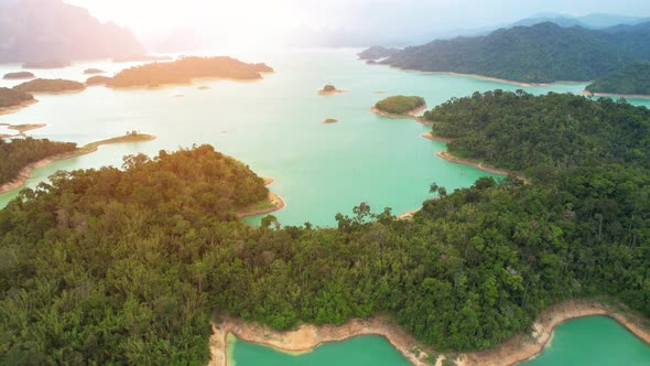 A drone flying over a dam in a beautiful tropical forest.