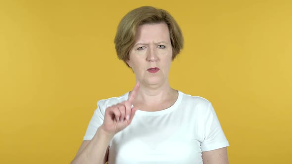 Old Woman Waving Finger to Refuse Isolated on Yellow Background