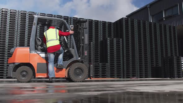 Warehouse worker driving forklift outside factory