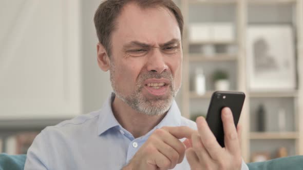 Senior Aged Businessman Reacting To Loss While Using Smartphone