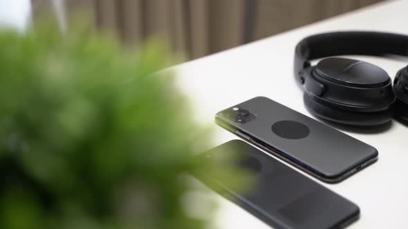 close up video of two dark smartphone and headphones on a white table