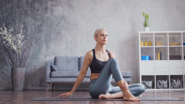 Young and sporty girl in sportswear is doing exercises in home interior.