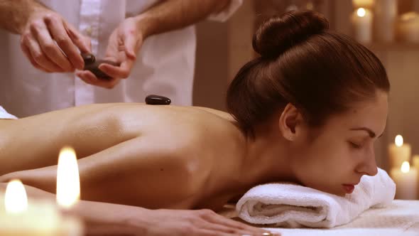 Calm Lady Enjoying Stone Massage in Spa Resort