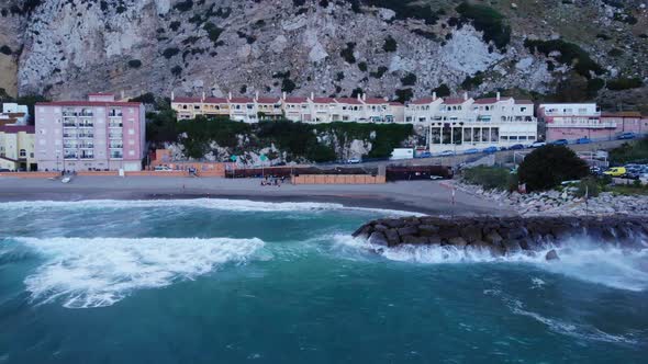 Crashing Waves Onto The Sea Walls At Catalan Bay In Gibraltar.Aerial Sideways Shot