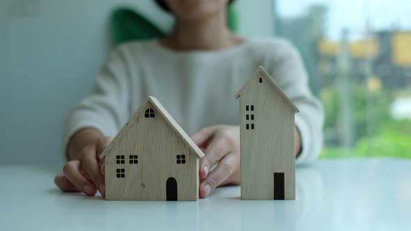 Closeup of a woman holding and showing wooden house model