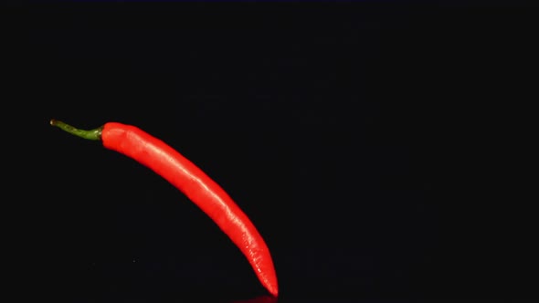 Super Slow Motion Sharp Red Chilli Falls on the Table