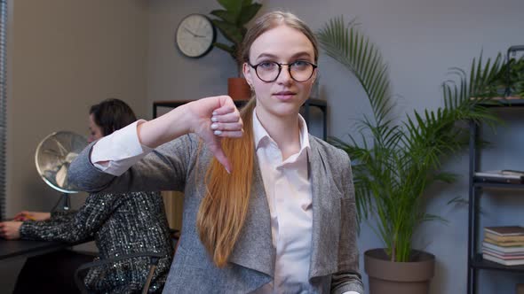 Unhappy Young Woman Secretary Making Thumb Down Gesture Expressing Discontent Disapproval in Office