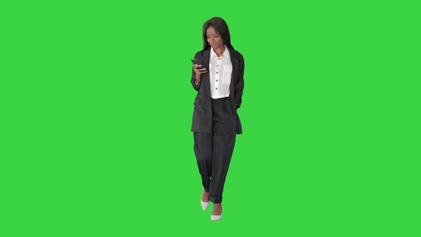 Smiling African American Female Texting on Phone While Walking on a Green Screen, Chroma Key.