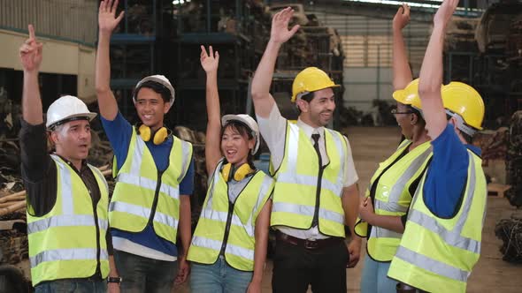 Group of engineers in uniforms and helmets in factory warehouse.