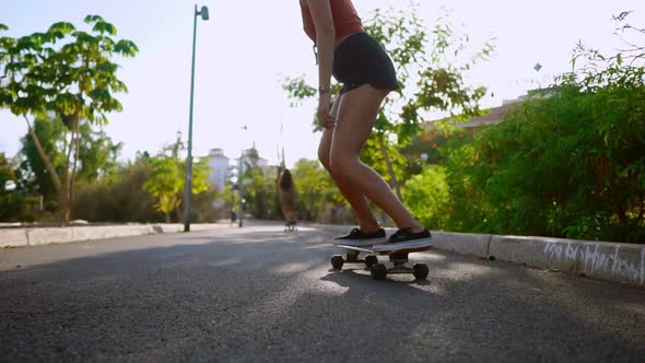 Woman Ride at Sunset Smiling with Boards for Skate Board Along the Path in the Park with Palm Trees