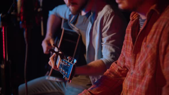 Two Men Sit on Stage and Sing a Song To the Guitar