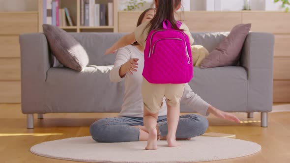 A girl runs into her mom and hug her from the front