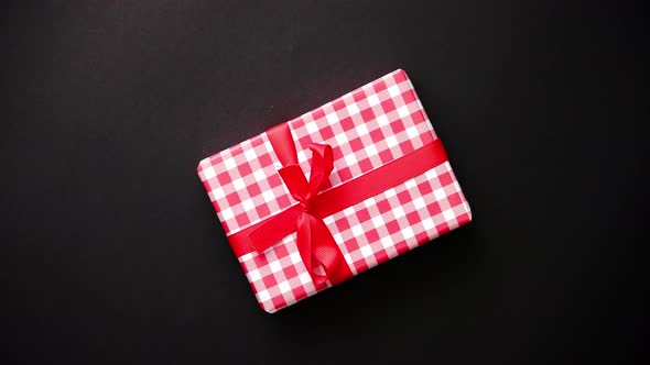 Red Gift Box with Red Bow on Black Table, Top View