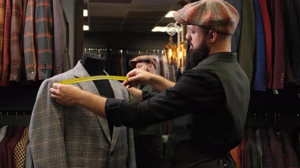 A Bearded Tailor Measures a New Quality Handmade Suit on a Mannequin in an Atelier. Creative Adult