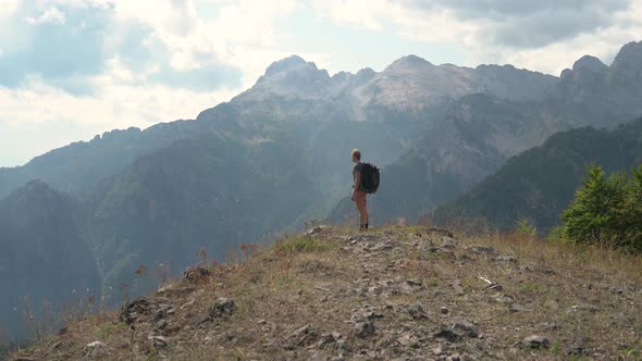 Man Hiker Tourist Walking on Edge of the Mountain and Looks Into the Distance