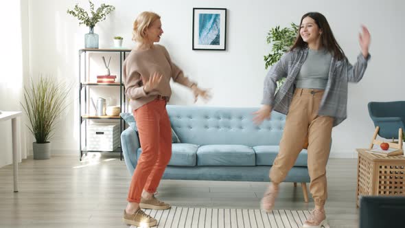 Mother and Daughter Danicng Having Fun and Laughing Indoors in Apartment