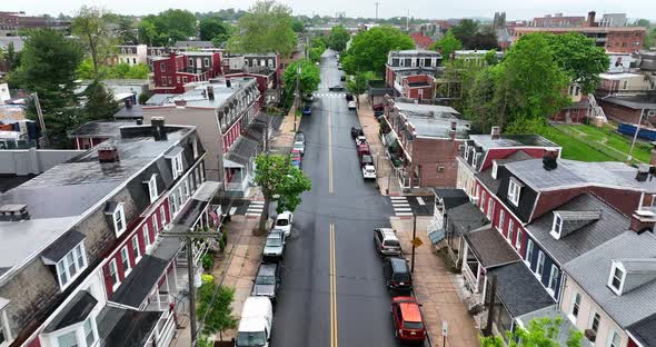 Aerial flight down city street. Ambulance passes through intersection. Low income one family homes l