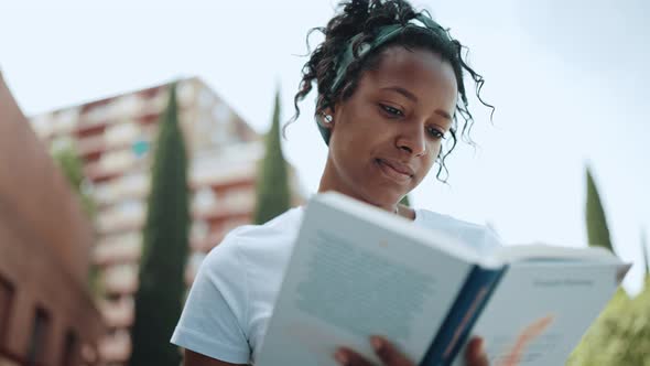 Positive brunette African woman reading book