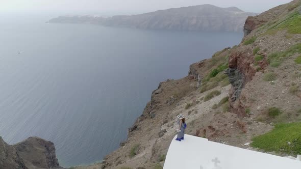 Aerial view woman standing in the edge of roof on Santorini traditional house.