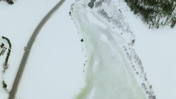 Cars Driving In A Narrow Road Across A Frozen Lake And Snow Covered Forests In Haugastol Norway - ae