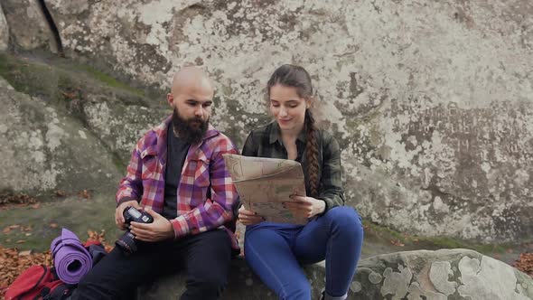 Photographer Traveling with a Camera, Tourist MAP and a Backpack Sitting with a Young Girl