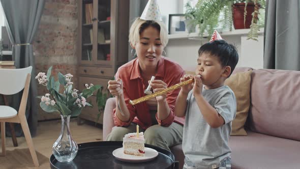 Asian Mother and Little Son Blowing Noisemakers