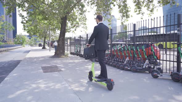 Young Businessman Riding Electric Scooter Outdoors.